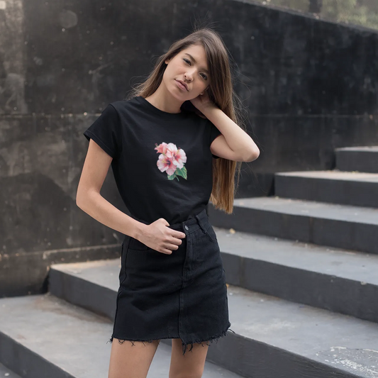 Woman wearing a black t-shirt with a floral design and black skirt standing on stone steps.
