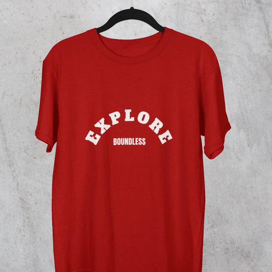 Red t-shirt with 'EXPLORE Boundless' text on a hanger against a gray concrete wall.