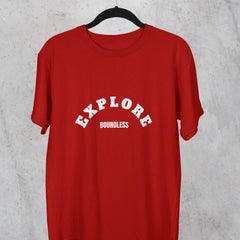 Red t-shirt with 'EXPLORE Boundless' text on a hanger against a gray concrete wall.