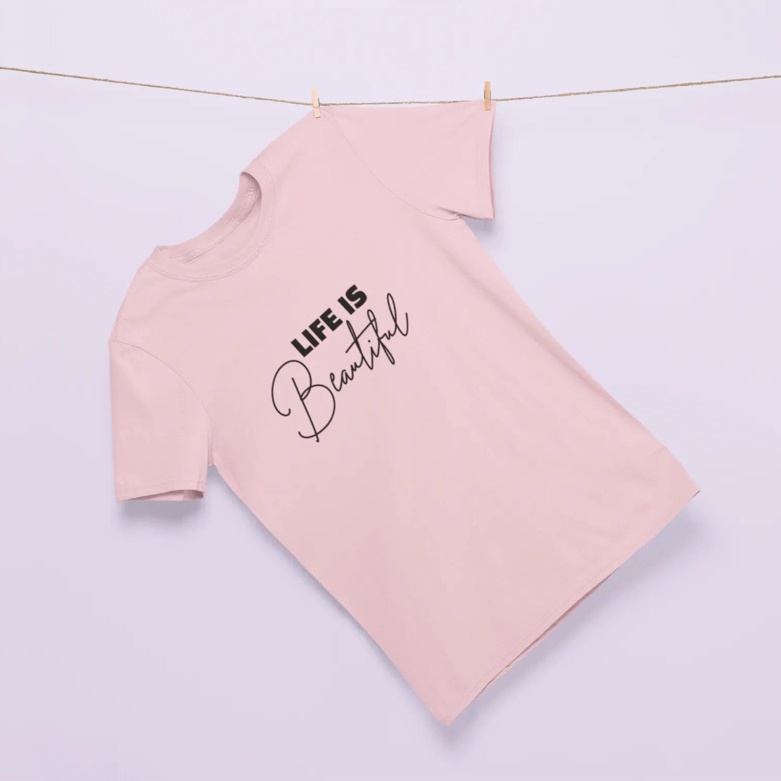 Pink long-sleeve shirt with 'Life is Beautiful' text on a light purple background