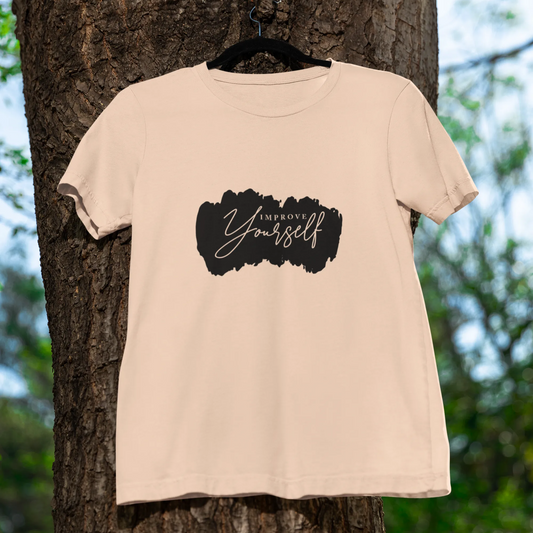 Beige t-shirt with a black graphic and text hanging on a tree