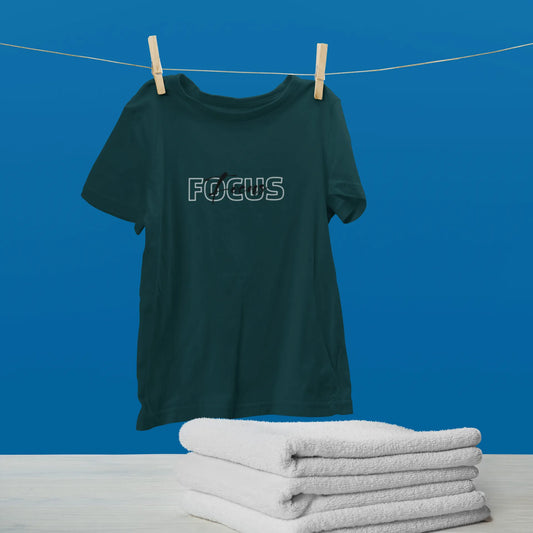 Green t-shirt with 'FOCUS' text on a clothesline against a blue background