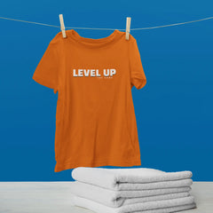 Orange t-shirt with 'LEVEL UP' text on a clothesline against a blue background