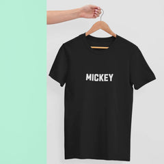 Black t-shirt with 'MICKEY' text on a hanger against a light green background