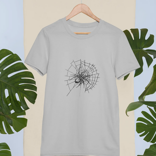 Gray t-shirt with black spider web design on a beige background with green leaves.