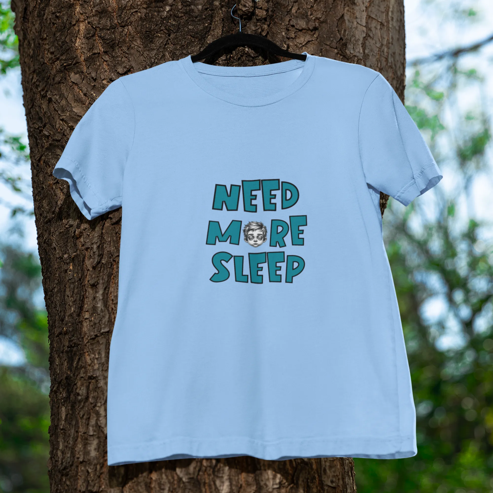 Light blue t-shirt with 'NEED MORE SLEEP' text hanging on a tree