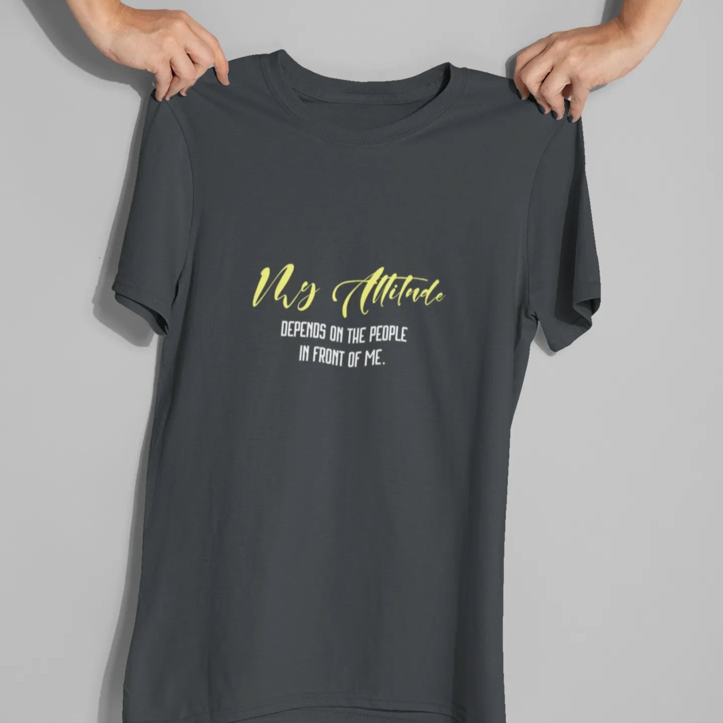 Black t-shirt with yellow text held by a person on a gray background