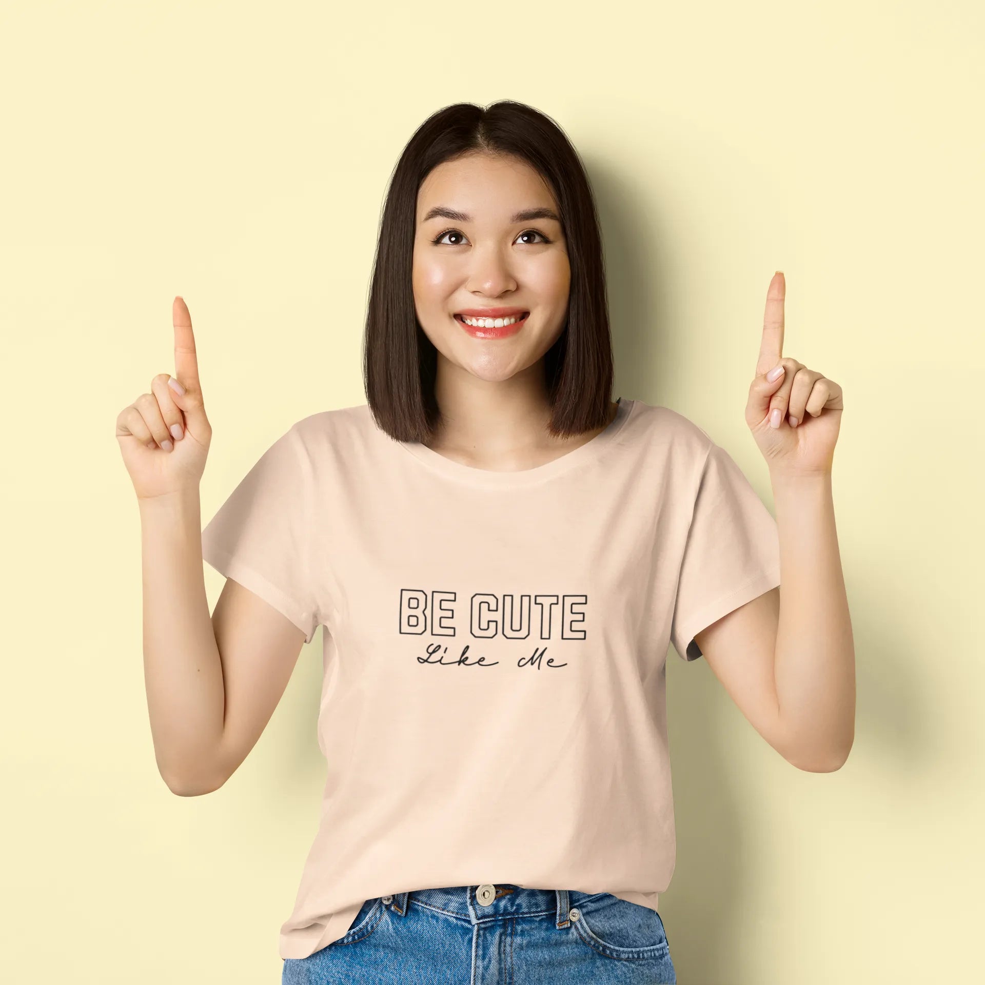 Woman wearing a beige t-shirt with 'BE CUTE like me' text on a light yellow background