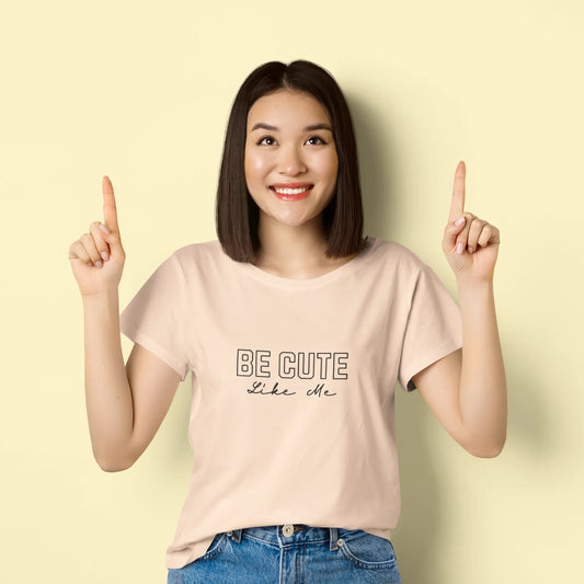 Woman wearing a beige t-shirt with 'BE CUTE like me' text on a light yellow background