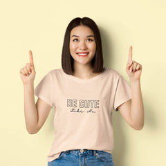 Woman wearing a beige t-shirt with 'BE CUTE like me' text on a light yellow background