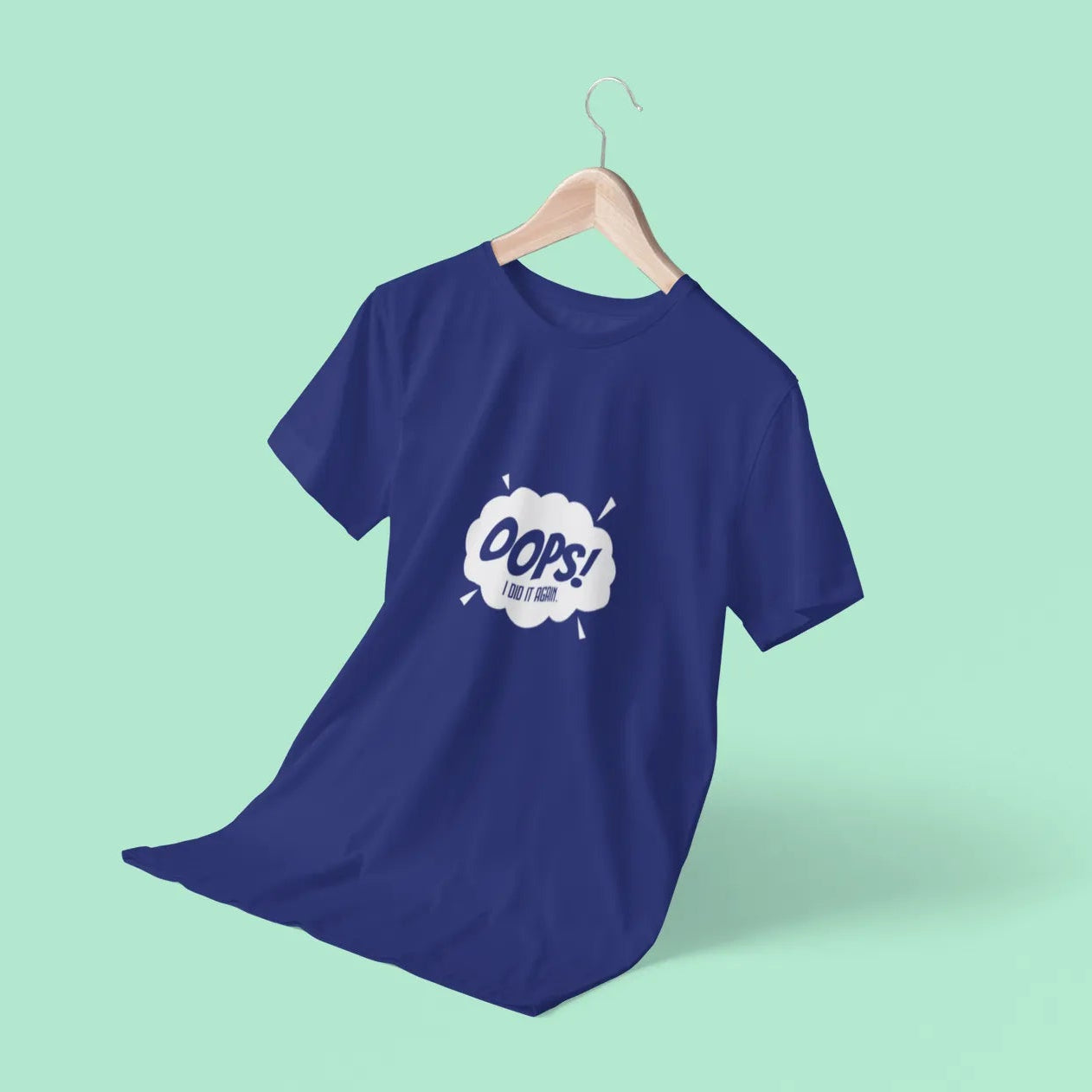 Blue t-shirt with a graphic design on a hanger against a light green background