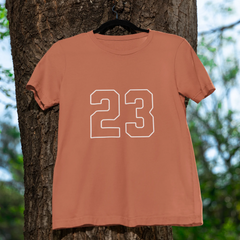 Coral t-shirt with the number 23 hanging on a tree