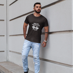 Man wearing a black t-shirt with text and light blue jeans standing against a white wall.