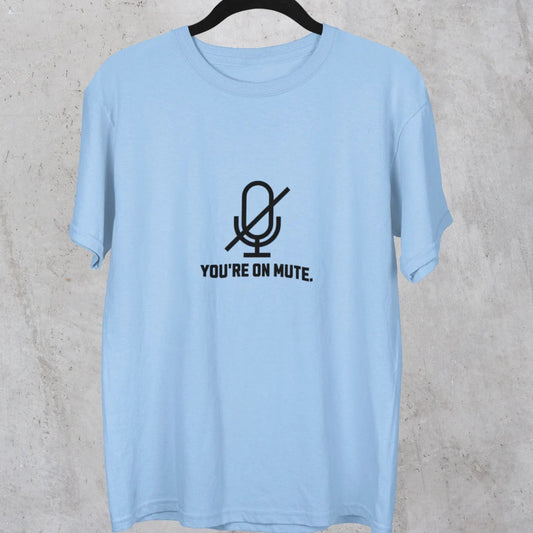 Light blue t-shirt with a microphone graphic and text on a hanger against a concrete wall.