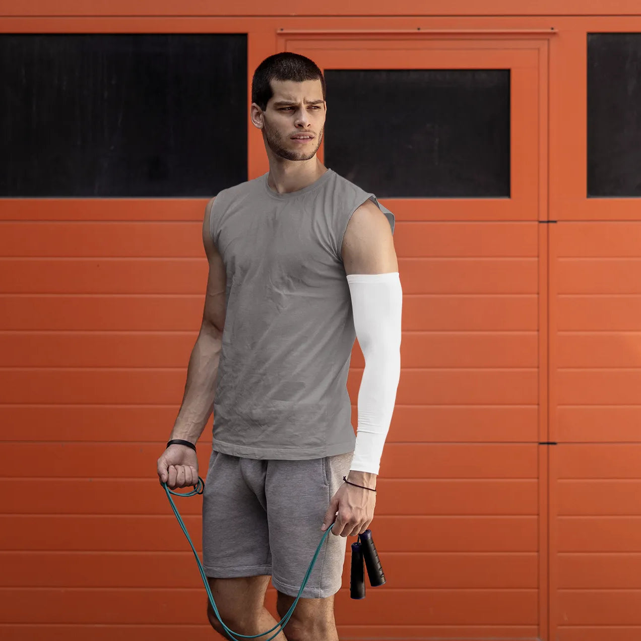 Man holding a jump rope in front of an orange wall