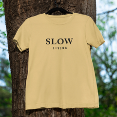 Beige t-shirt with 'SLOW LIVING' text hanging on a tree