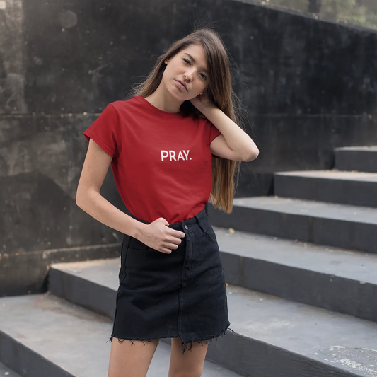 Woman wearing a red t-shirt with 'PRAY.' text on black steps.