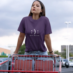 Woman wearing a purple t-shirt with a smiley face design, standing next to a shopping cart in an outdoor setting.