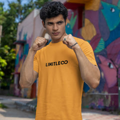 Person wearing a mustard yellow t-shirt with 'LIMITLESS' text in front of a colorful mural.