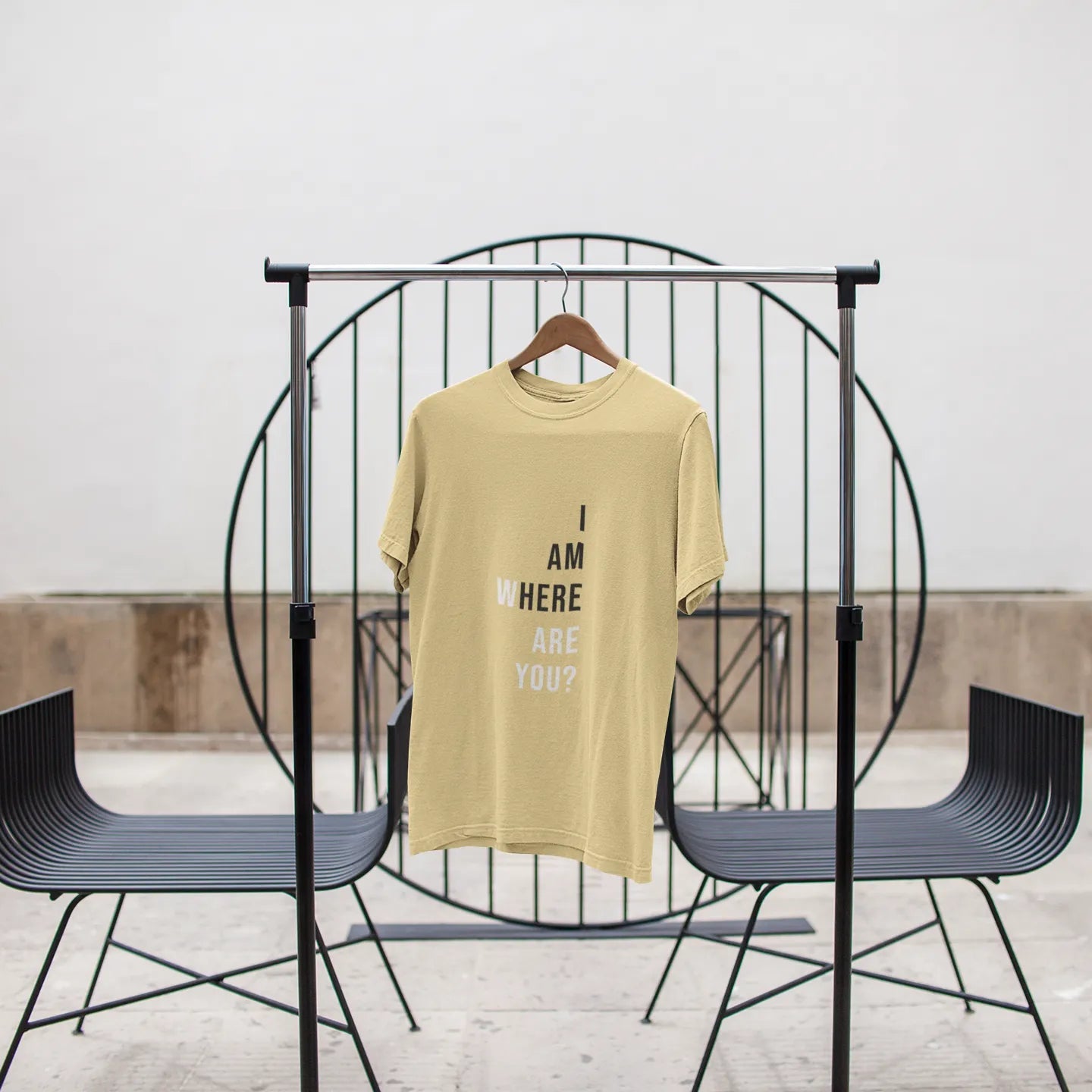 Yellow t-shirt with text on a black metal stand against a white wall.