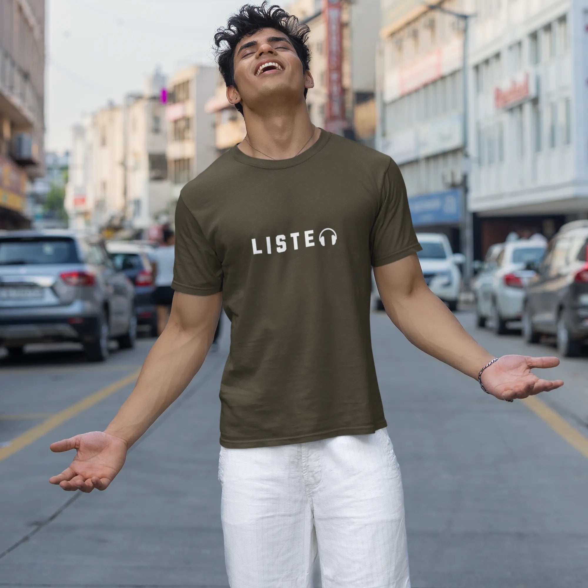 Person wearing a green t-shirt with 'LISTEN' printed on it, standing on a city street.