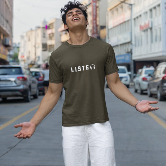 Person wearing a green t-shirt with 'LISTEN' printed on it, standing on a city street.