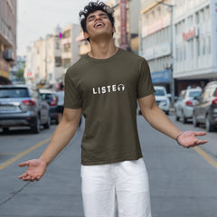 Person wearing a green t-shirt with 'LISTEN' printed on it, standing on a city street.