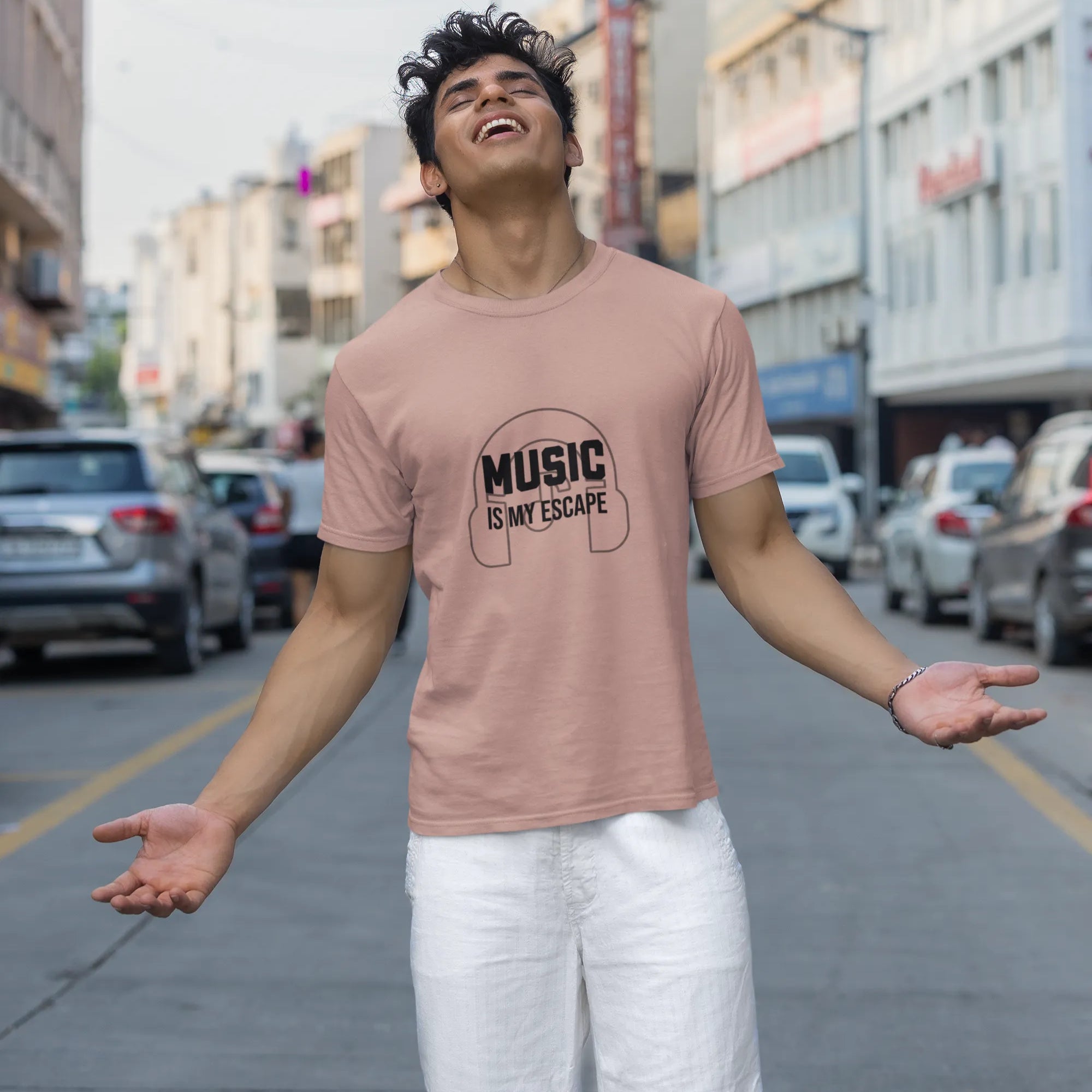 Person wearing a pink t-shirt with 'Music is my escape' text on a city street.