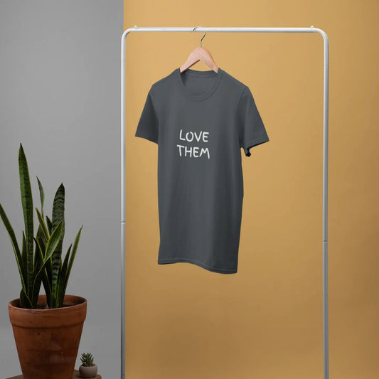 Gray t-shirt with 'LOVE THEM' text on a white rack against a yellow wall.