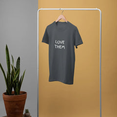 Gray t-shirt with 'LOVE THEM' text on a white rack against a yellow wall.