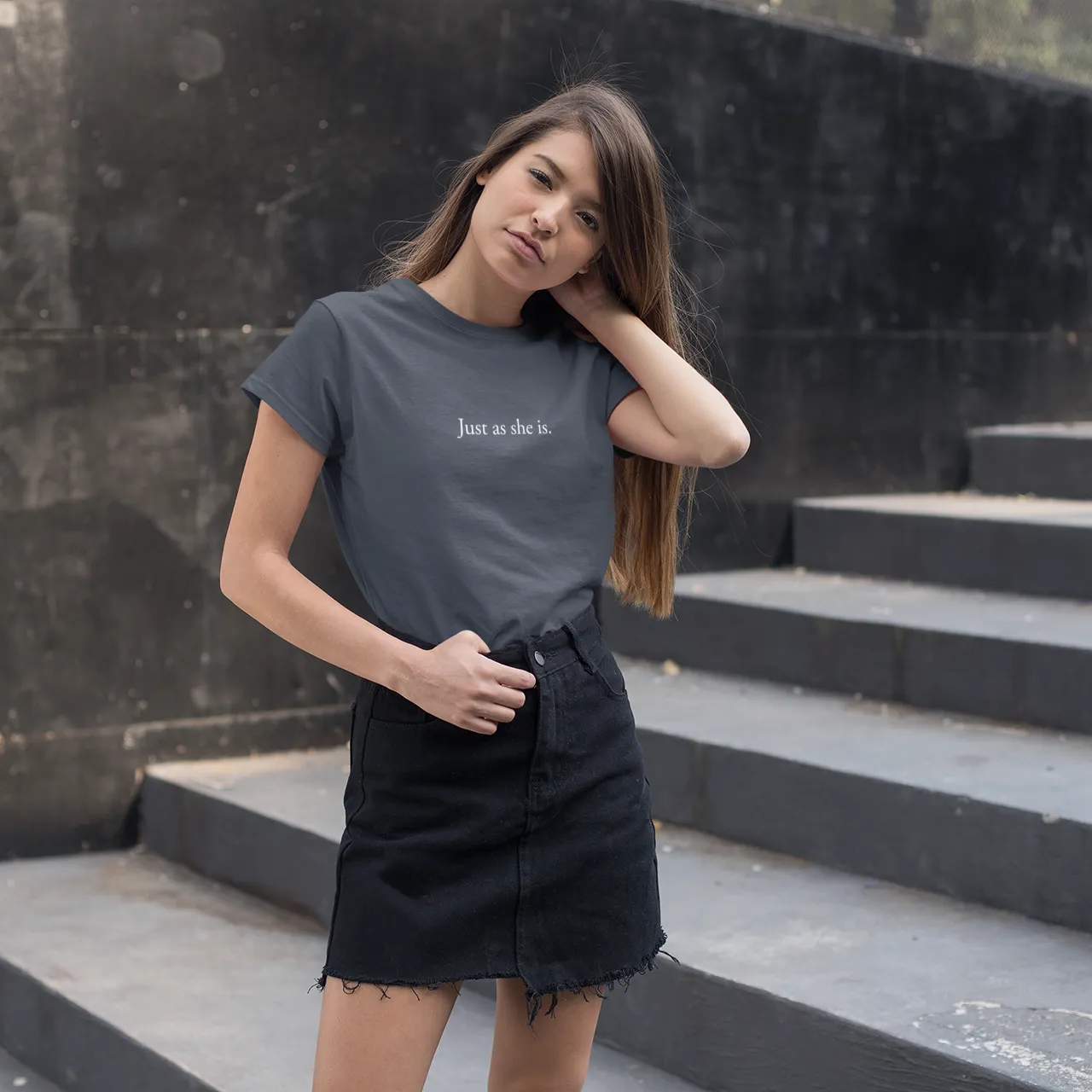 Woman wearing a dark gray t-shirt with text on it, standing on stone steps.