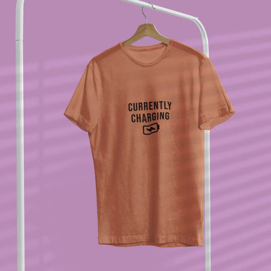 Brown t-shirt with 'Currently Charging' text on a hanger against a purple background