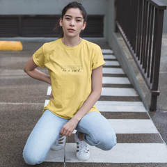 Person wearing a yellow t-shirt sitting on a concrete step.