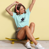 Woman sitting on a skateboard with arms raised against a yellow background