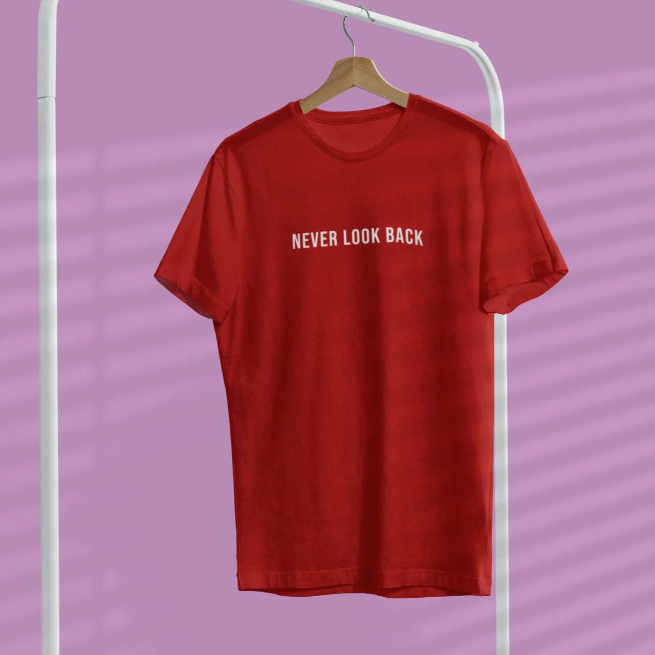Red t-shirt with 'NEVER LOOK BACK' text on a hanger against a purple background