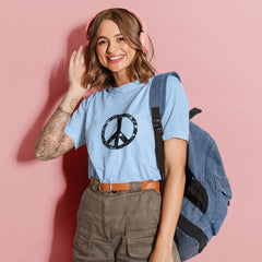 Woman wearing a light blue t-shirt with a peace symbol, carrying a backpack on a pink background
