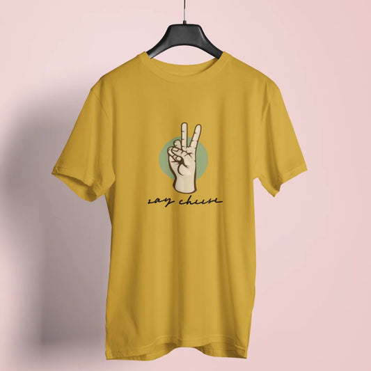 Yellow t-shirt with a peace sign design on a hanger against a pink background