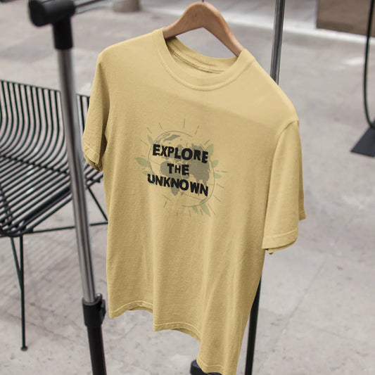 Yellow t-shirt with 'Explore the Unknown' text on a hanger against a blurred indoor background