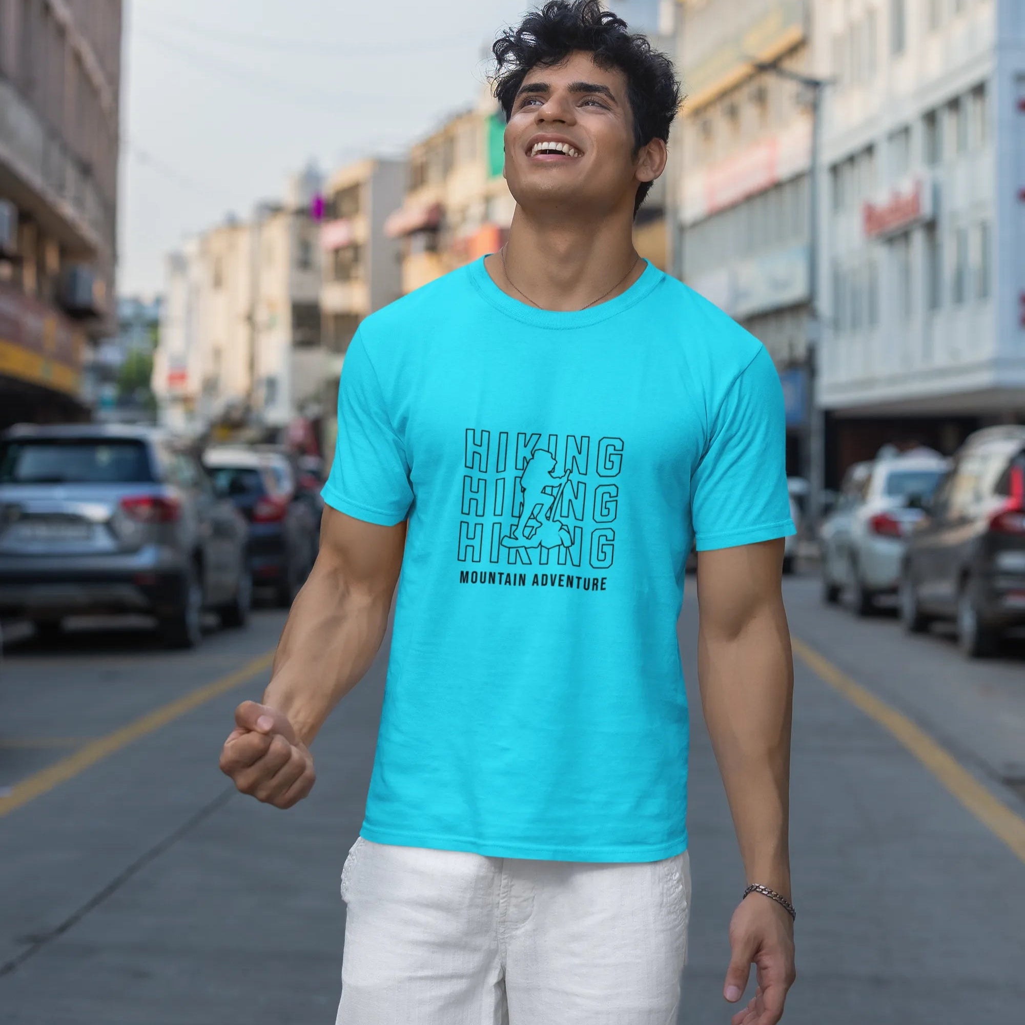 Man wearing a turquoise t-shirt with text on a city street