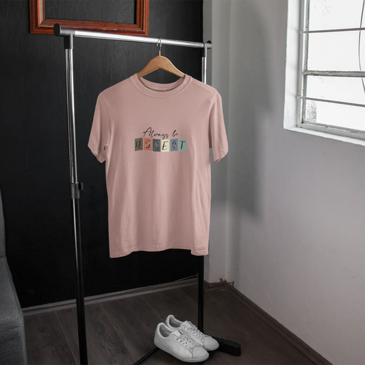 Pink t-shirt with colorful text on a hanger in a room with a window.
