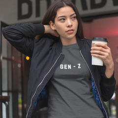 Woman wearing a 'GEN-Z' t-shirt holding a coffee cup outdoors.