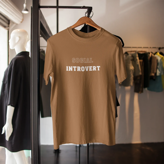Brown t-shirt with 'SOCIAL INTROVERT' text on a hanger in a store setting.