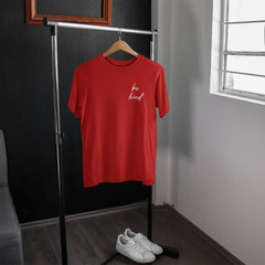 Red t-shirt with 'be kind' text on a hanger in a room with a window.