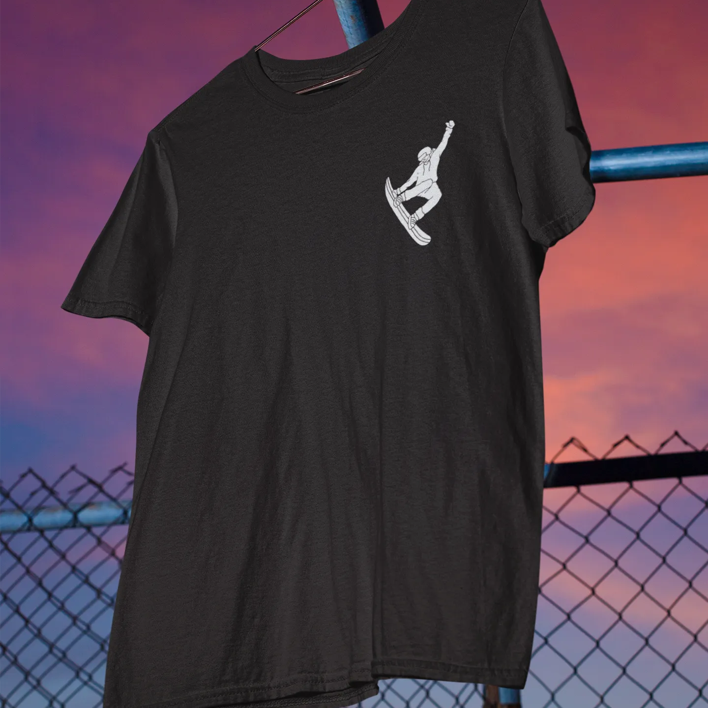Black t-shirt with a white graphic on a metal pole against a sunset sky.