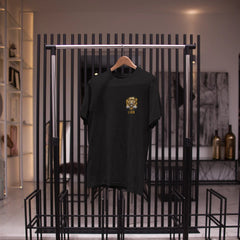 Black t-shirt with a logo on a black metal clothing rack.