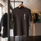 Black t-shirt with 'MOON' logo on a hanger in a clothing store.
