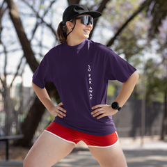 Woman wearing a purple t-shirt and red shorts standing outdoors with trees in the background