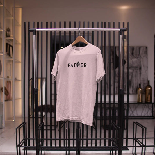 Light gray t-shirt with 'FATHER' printed on it hanging on a black rack.