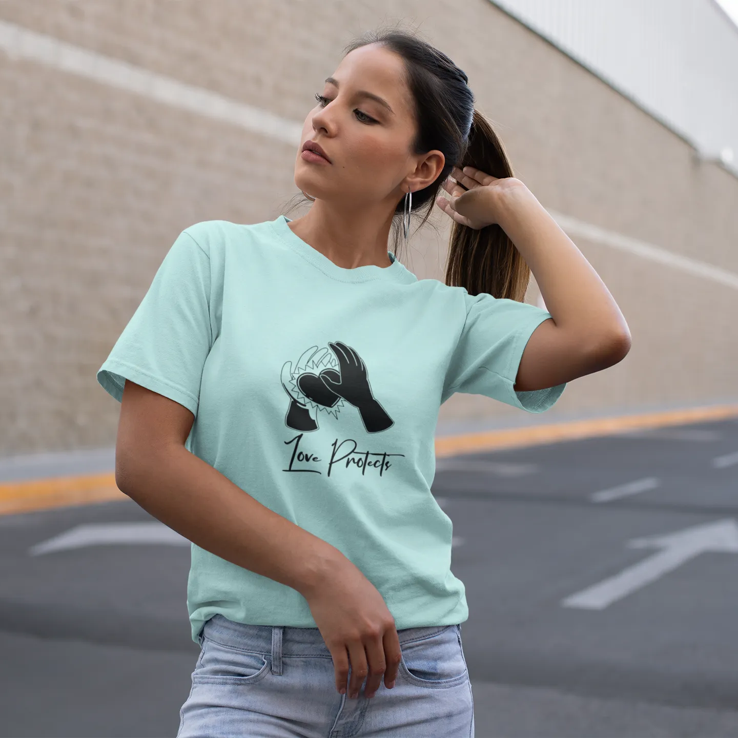 Woman wearing a light blue t-shirt with a graphic design and text, standing on a street.