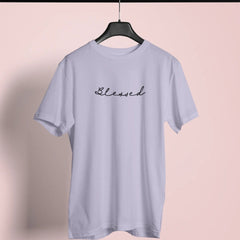 Light blue t-shirt with 'Blessed' text on a hanger against a pink background